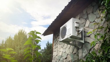 Dışarıdaki evin ön cephesindeki taş bir duvarda klima var. Bir banliyö evinin iklim kontrolü
