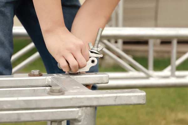 Worker assemble a mobile stage from trusses for a outdoor concert.