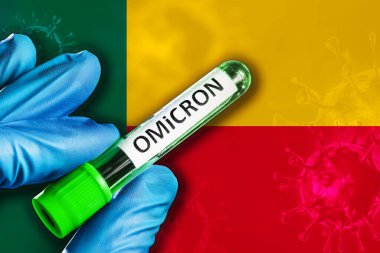 Benin salgını Omikron varyantı. Mavi lastik eldivenli bir el, Benin bayrağının önünde kovid 19 virüslü bir tüp tutuyor. Omicron varyant salgını kavramı