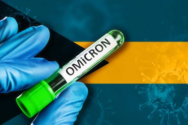 Bahamalar Omikron salgını. Mavi lastik eldivenli bir el Bahamalar bayrağının önünde üzerinde kovid 19 virüsü olan bir tüp tutuyor. Omicron varyant salgını kavramı