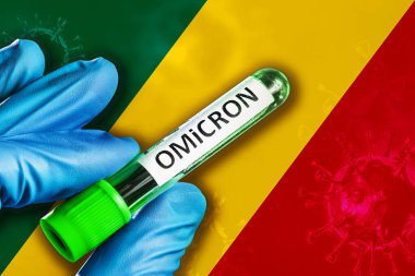 Kongo salgını Omikron varyantı. Mavi lastik eldivenli bir el Kongo bayrağının önünde üzerinde covid-19 virüsü olan bir tüp tutuyor. Omicron varyant salgını kavramı