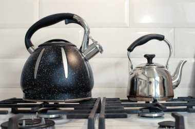 Gaz ocağında büyük ve küçük metal çaydanlık.