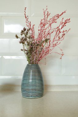 Ev mutfak masasının üzerinde bitkisel bitki içeren dekoratif küçük vazo.