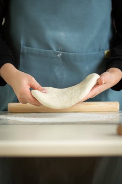 Mavi önlüklü bir aşçının elinde rulo hamur vardır. El görünümü, dikey kopyalama alanı.