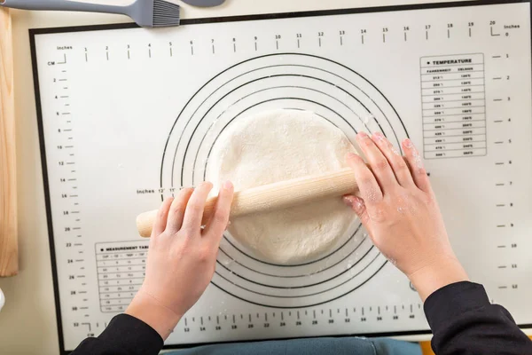 Rolling out dough on a silicone baking mat with round markings of different diameters, top view.