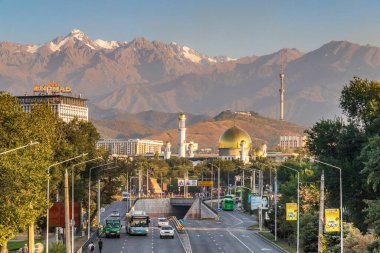 Suyunbay Avenue and the intersection with Raiymbek Street against the backdrop of a mosque and mountains in the city of Almaty clipart