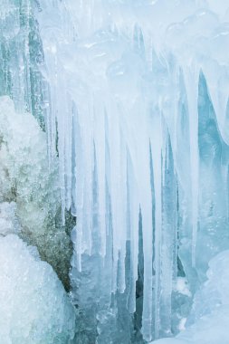 Buzdan, buz saçaklarından, donmuş su damlalarından oluşan kışın dikey arka planı.
