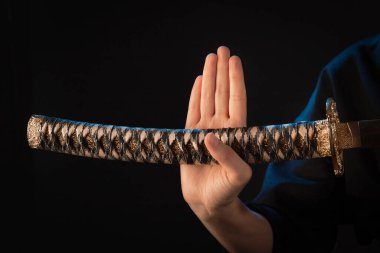 Japon yapımı Wakizashi kabzalı bir silahla bir kadının eline yakın çekim..
