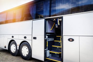 Açık kapısı olan büyük beyaz bir turist otobüsünün yanında..