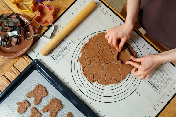 A woman cooking holiday homemade cookies on a silicone baking mat. Top view.