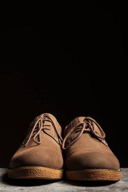 Siyah arka planda bağcıkları olan erkek süet kahverengi alçak ayakkabılar. Dikey kopyalama alanı