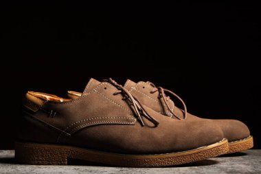 Side view of brown shoes with laces on a black background