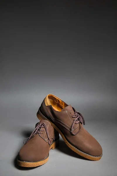 Zapatos de gamuza marrón sobre fondo gris con espacio de copia vertical —  Fotos de Stock