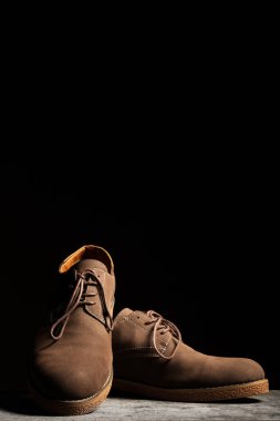 Dikey kopyalama alanı olan siyah bir arkaplanda kahverengi ayakkabılar.