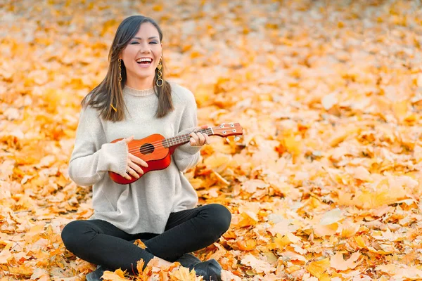 Genç Mutlu Bir Kadın Düşen Sonbahar Yapraklarının Üzerinde Müzik Aletleriyle — Stok fotoğraf