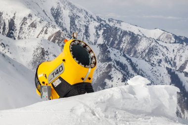 Almaty, Kazakistan - 16 Mart 2021: kayalık dağ yamacına karşı kar topu. Kar yapma makinesi kayak yamaçlarında