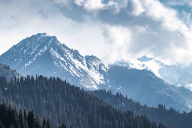 Daytime snowy mountain landscape with copy space in the cloudy sky.