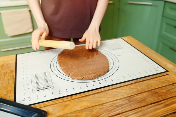 Rolling out shortcrust pastry for home bakery on a silicone baking mat on a wooden table.