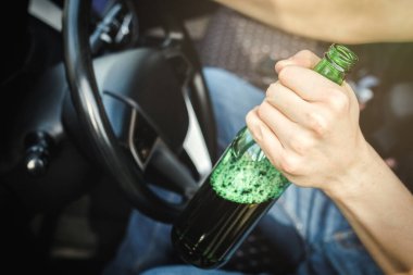 Alkolik sürücü elinde bira şişesiyle araba kullanıyor..