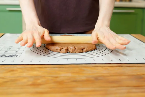 Rolling out gingerbread dough on a silicone baking mat on a wooden table with copy space.