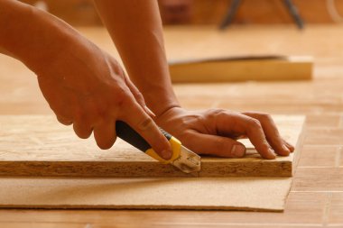 Sipariş vermek için mobilya yaparken fiberboard kesen bir marangozun yan görüntüsü.