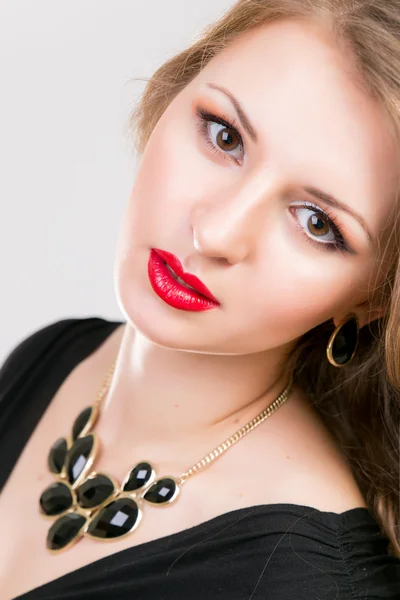 Young beautiful girl with make-up and hairstyle in black dress and big jewelry Royalty Free Stock Images