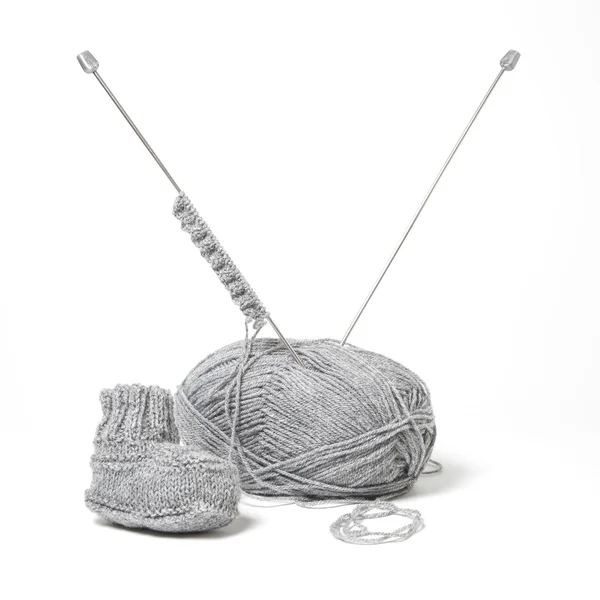 A little bootie by a knitting equipment — Stock Photo, Image