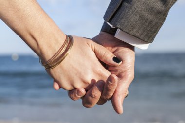 A couple holding hands by the sea. clipart