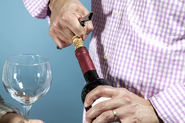 A man uncorking a bottle of red wine — Stock Photo, Image