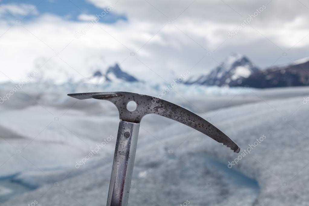 Silvered ice axe fixed on ice, with a glacier landscape background