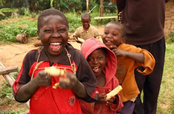 Niños ugandeses felices comiendo caña de azúcar Imagen de stock