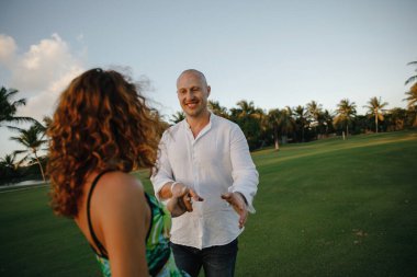 Dominik Cumhuriyeti 'ndeki tropikal bir adada golf kulübünde yürüyüş yapan güzel bir çift öpüşüyor ve sarılıyor.