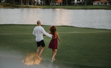 Dominik Cumhuriyeti 'ndeki tropikal bir adada golf kulübünde yürüyüş yapan güzel bir çift öpüşüyor ve sarılıyor.