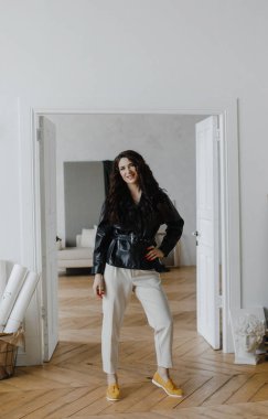 Güzel kıvırcık saçlı, deri ceketli esmer bir kız lüks saçlar için poz veriyor.