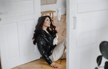 Güzel kıvırcık saçlı, deri ceketli esmer bir kız lüks saçlar için poz veriyor.