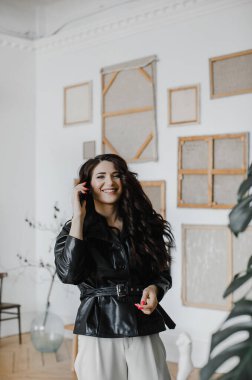 Güzel kıvırcık saçlı, deri ceketli esmer bir kız lüks saçlar için poz veriyor.