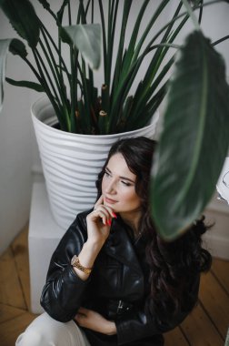 Güzel kıvırcık saçlı, deri ceketli esmer bir kız lüks saçlar için poz veriyor.