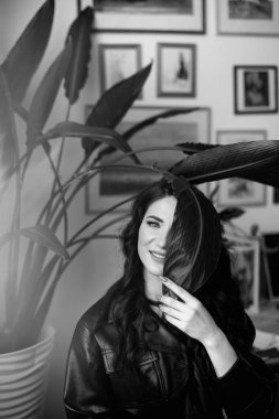 Güzel kıvırcık saçlı, deri ceketli esmer bir kız lüks saçlar için poz veriyor.