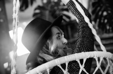 Kısa siyah elbisesi, şapkası ve ayakkabıları olan güzel, seksi, duygusal bir kız bir partide şık bir stüdyoda poz veriyor.