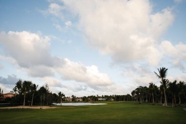 Dominik Cumhuriyeti 'ndeki tropik bir adadaki seçkin bir golf kulübünün inanılmaz manzaraları tilki kuyruğu ve hindistan cevizi palmiyeleri, yeşil yapraklar, tarlalar, göl...