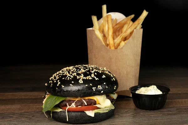Czarny burger na tablicy z frytkami — Zdjęcie stockowe