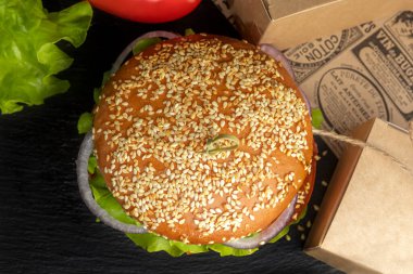 Koyu arkaplanda hamburger ve patates kızartması.