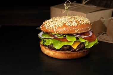 Koyu arkaplanda hamburger ve patates kızartması.