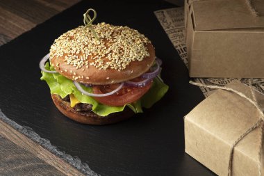 Koyu arkaplanda hamburger ve patates kızartması.