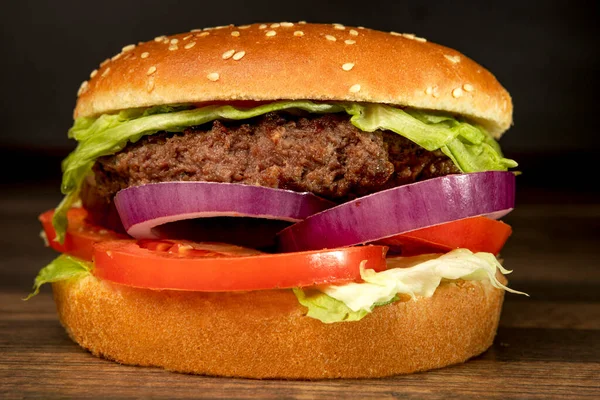 Koyu arkaplanda hamburger ve patates kızartması.
