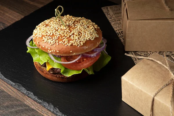 Koyu arkaplanda hamburger ve patates kızartması.