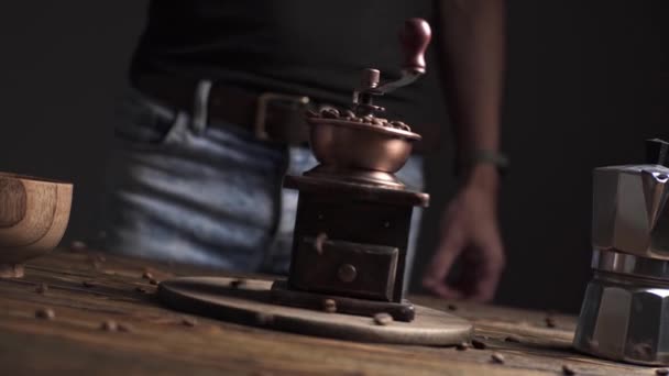 어두운 배경 의나무 탁자 위에 손으로 커피 분쇄기를 놓고 향기 로운 커피 원두를 갈고 있는 모습. — 비디오