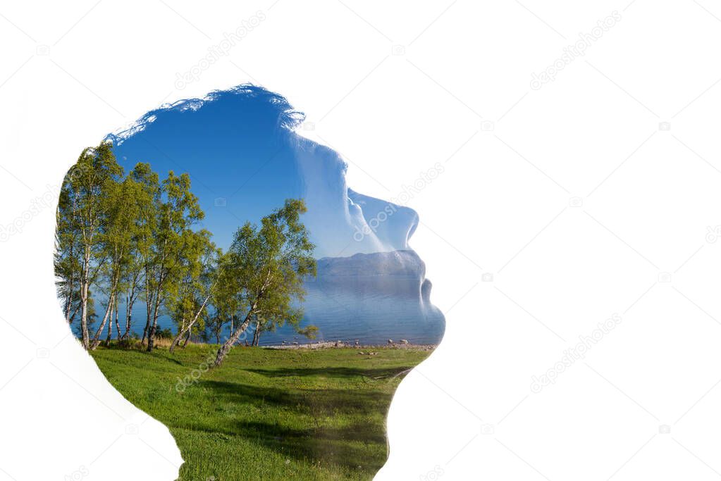 Combination of a silhouette of a face and a landscape with trees, grass, sky and water. Concept of the connection between man and nature