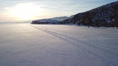 Güneşli bir günde, karla kaplı Baykal Gölü 'nün, kayalar ve tepelerle kaplı kış manzarası. Bir İHA 'dan ateş etmek