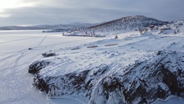 Zimní krajina zasněženého jezera Bajkal se skalami a kopci za slunečného mrazivého dne. Střelba z dronu — Stock video